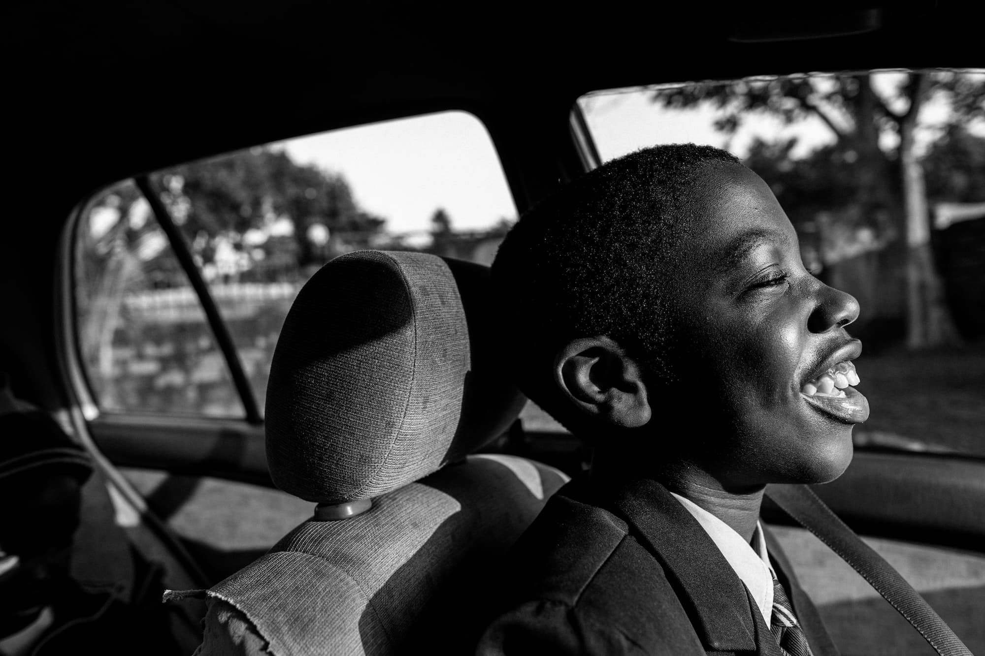 Black boy sitting in the front seat of a car going to school