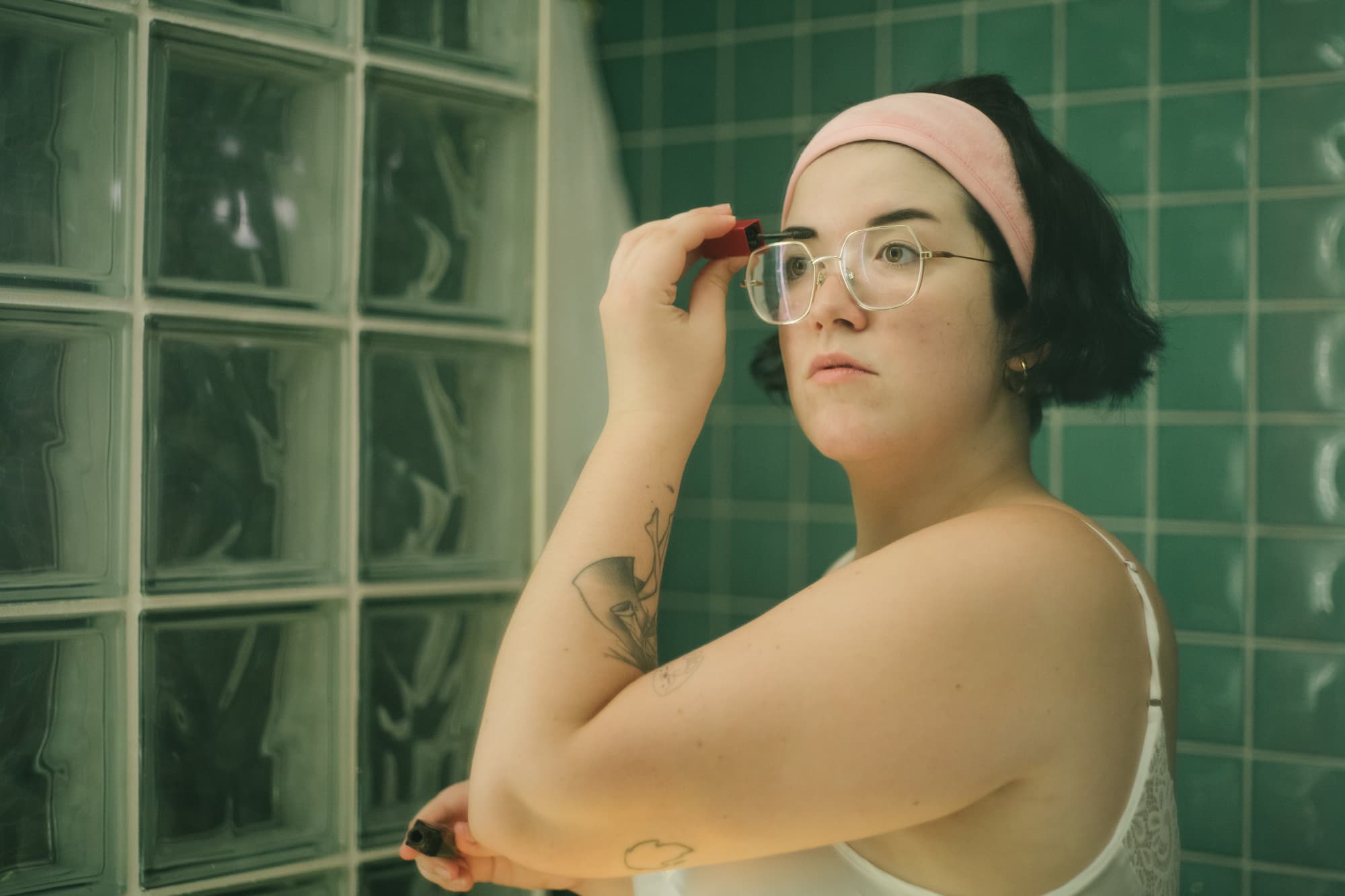 Young woman doing her brows on her bathroom mirror