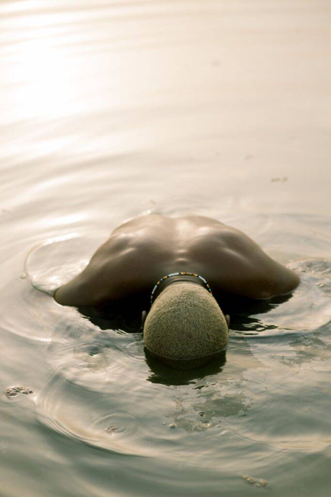 A dark skin model with a blonde hair in a river.
