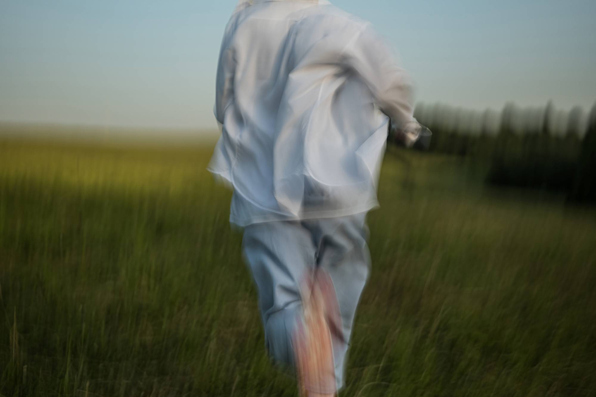 Running through the green grass of a spacious summer field. Emotional cinematic effect.