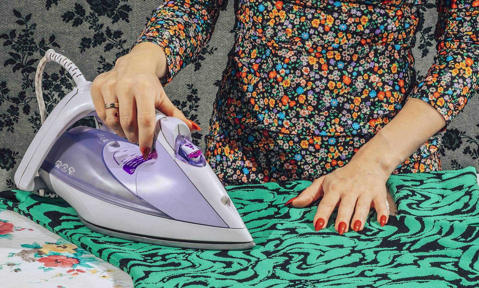 Female hands pressing iron while ironing clothes.