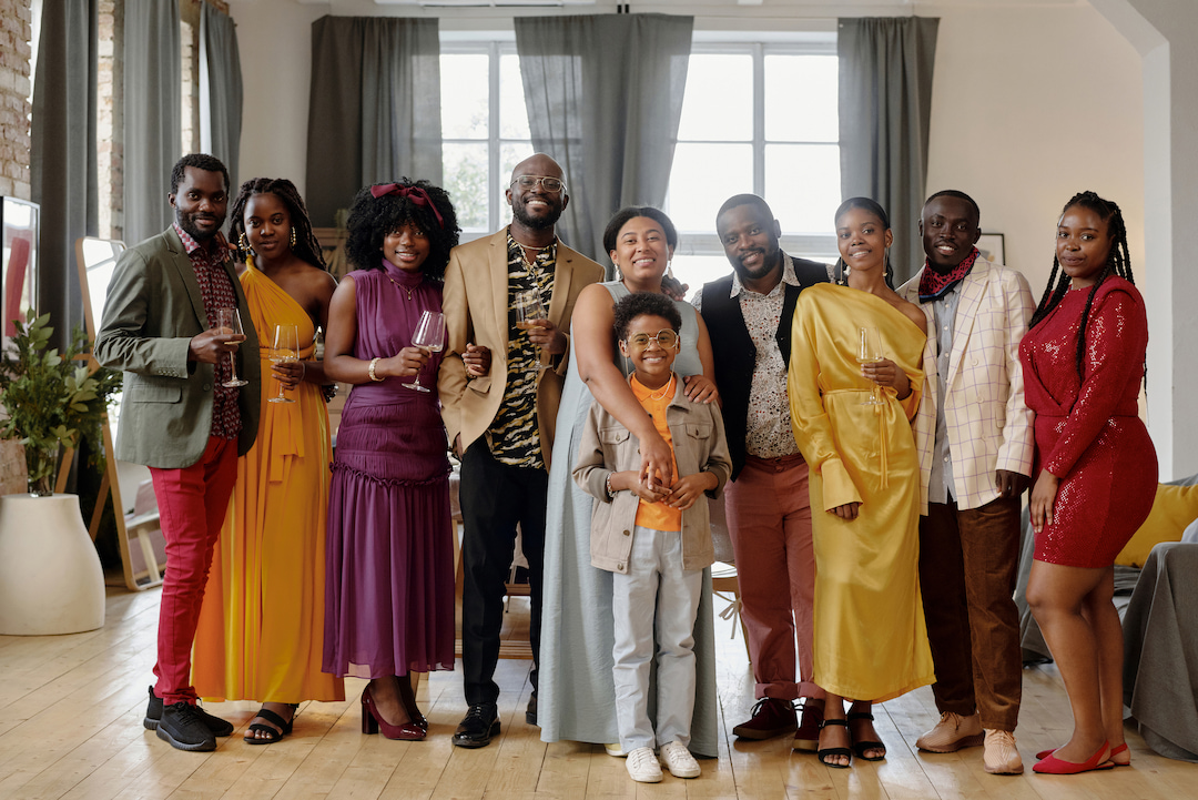 Horizontal long shot portrait of modern big African American family wearing fancy outfits spending time together at party at home looking at camera