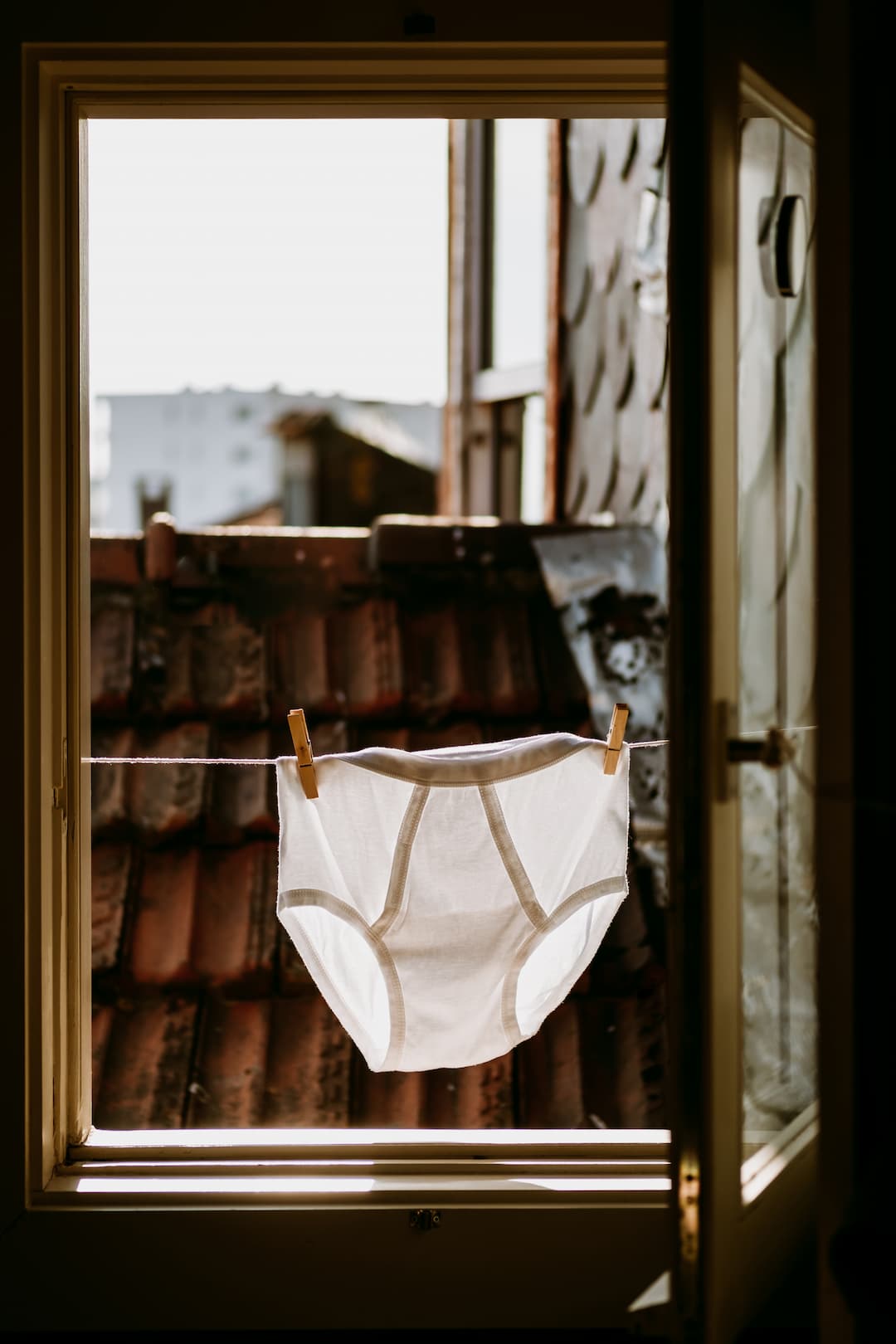 man's panties drying on a wire at a window, in the sun