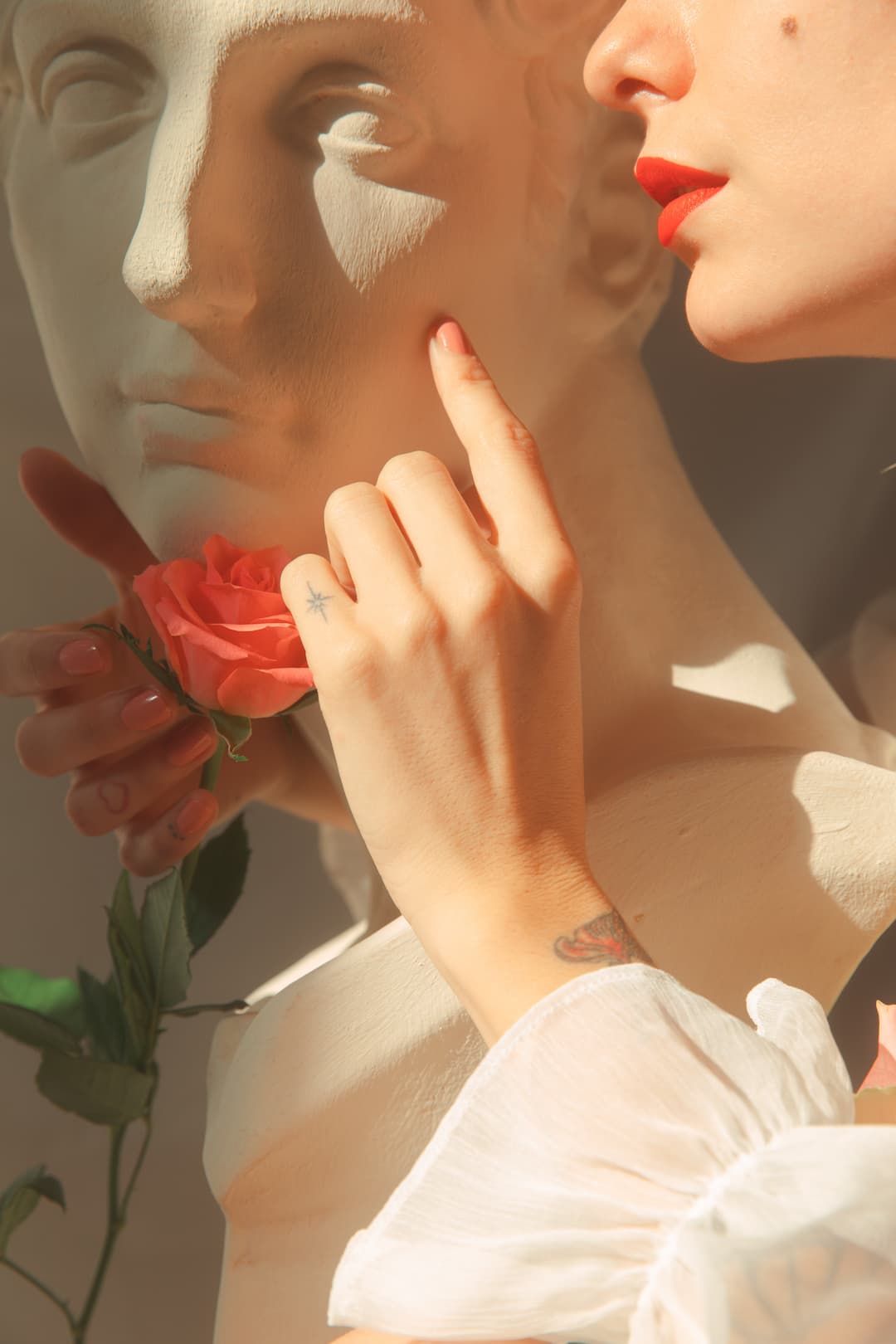 romantic scene of anonymous woman caressing greek statue surrounded by roses.