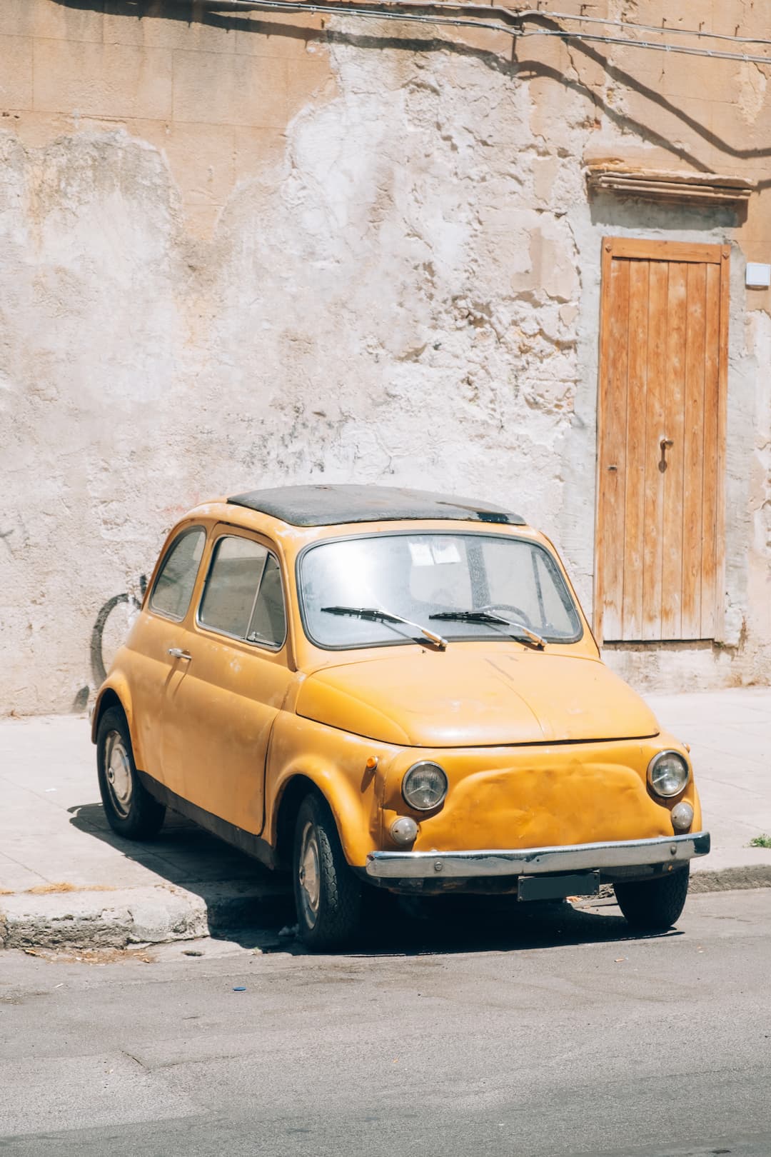 Street detail with old classic italian car parked on street in Sicily.