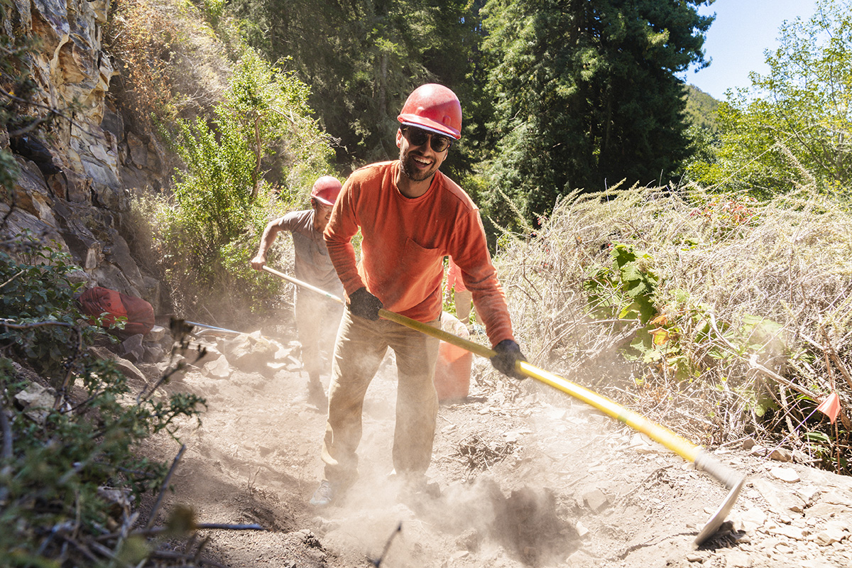 A person volunteering to help build and maintain outdoor recreational trails for hiking and biking in the forest.