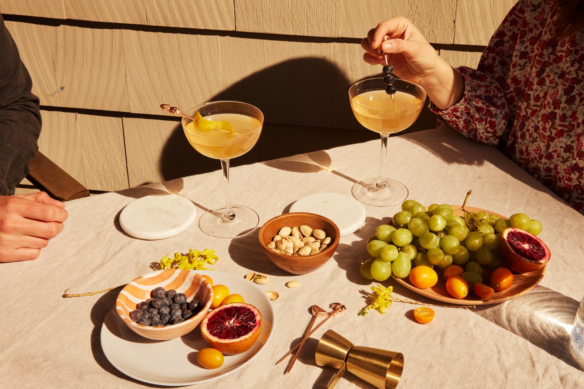 Couple having cocktails sitting at a table filled with different foods