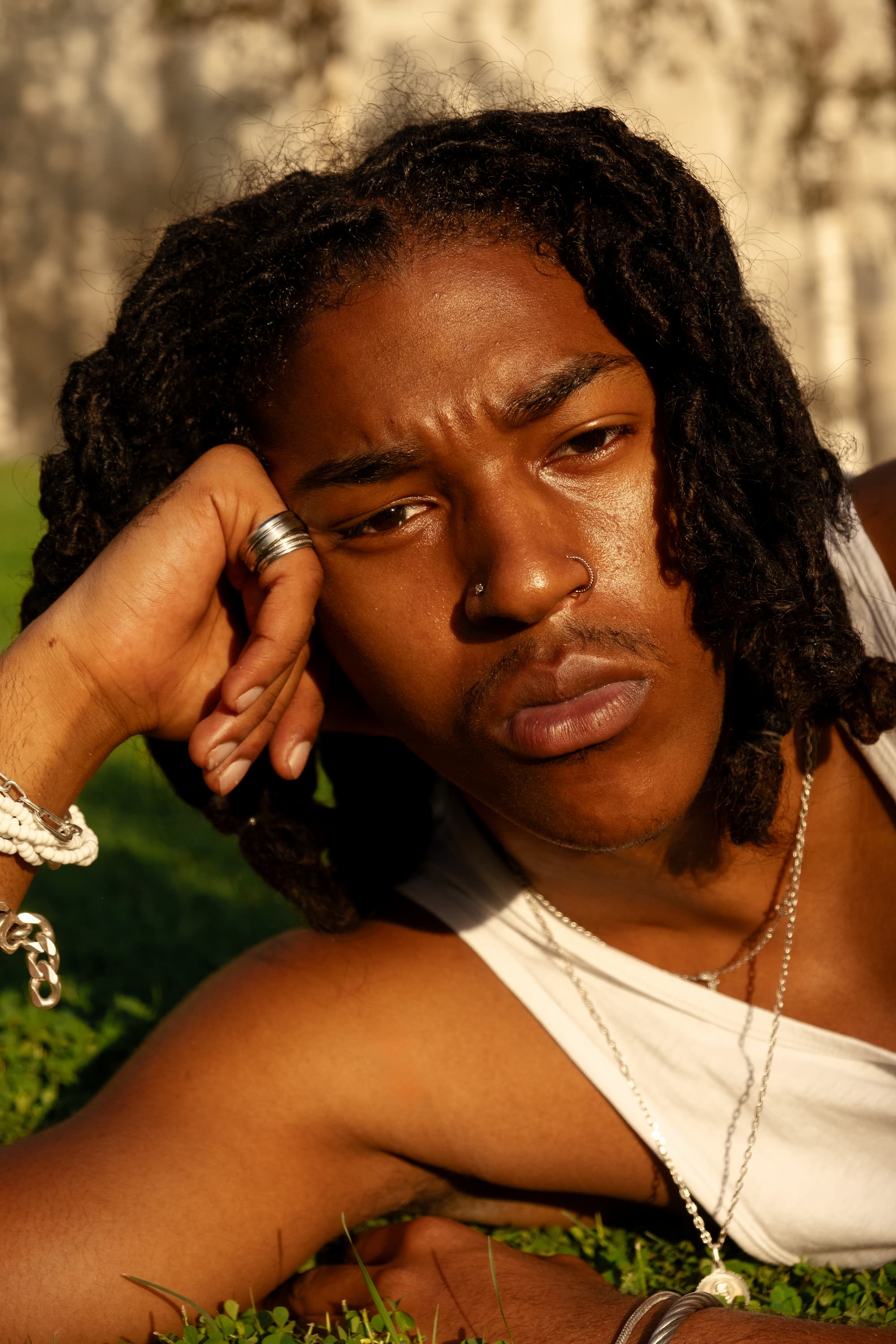 Portrait of black man with braids lying on grass in a park.