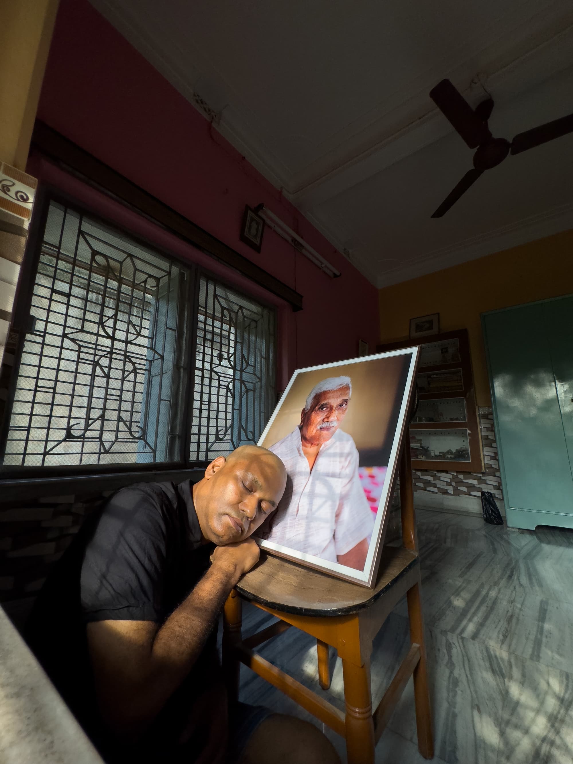 Indian man offering respect to his deceased father inside a house