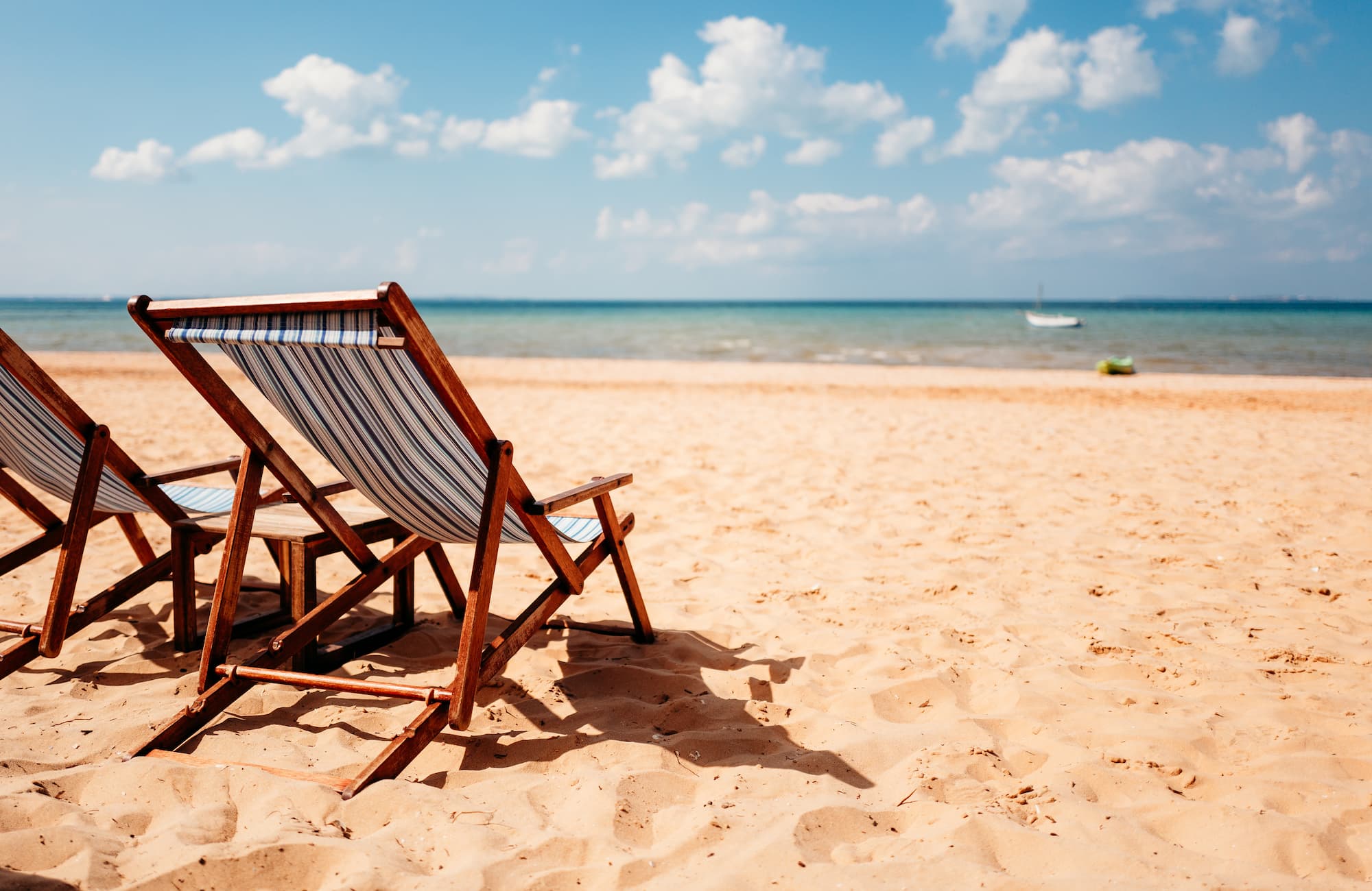 2 blue and white striped deckchairs on a tropical beach.