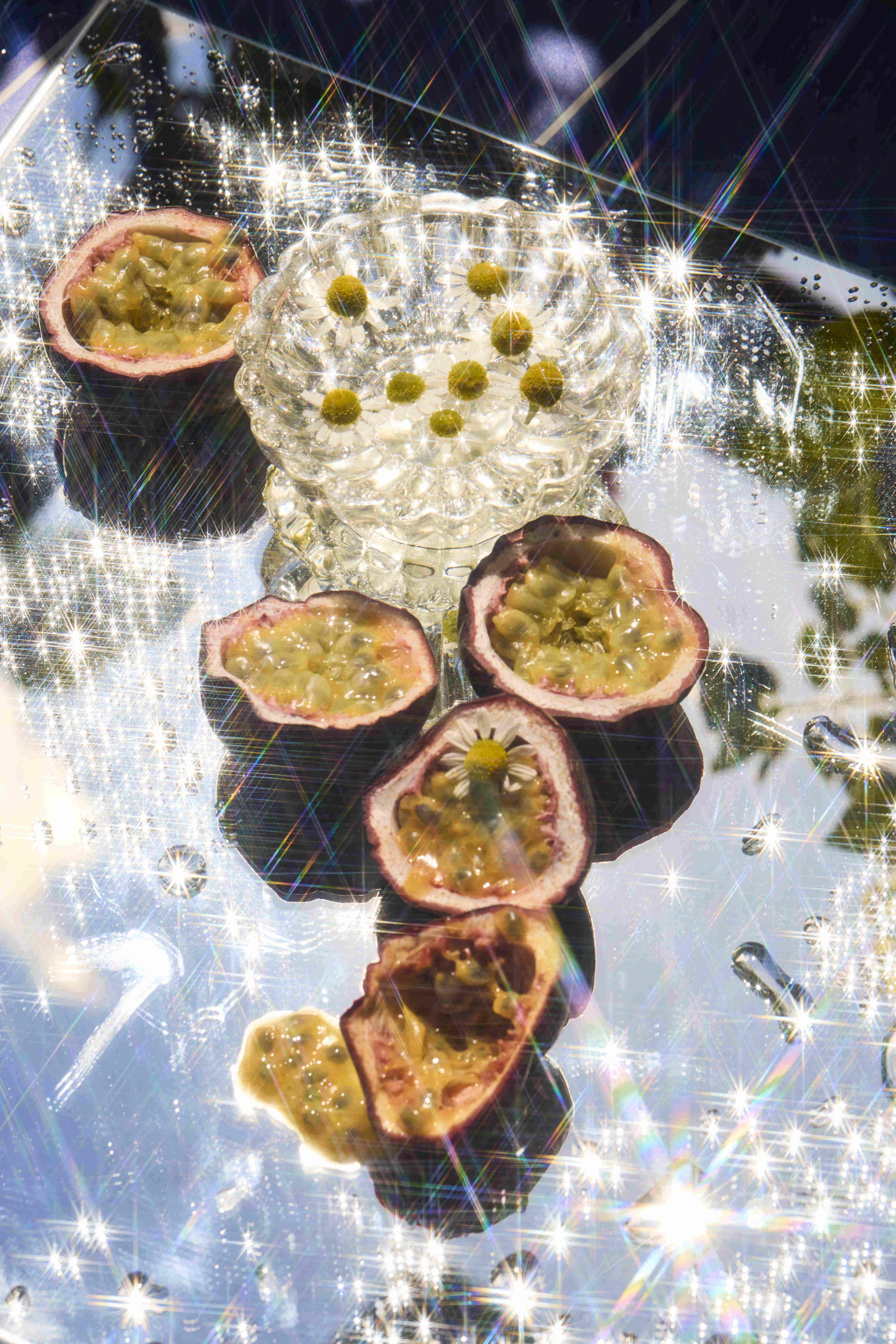 Various split passionfruits that are laid on a glass mirror with reflections and refractions