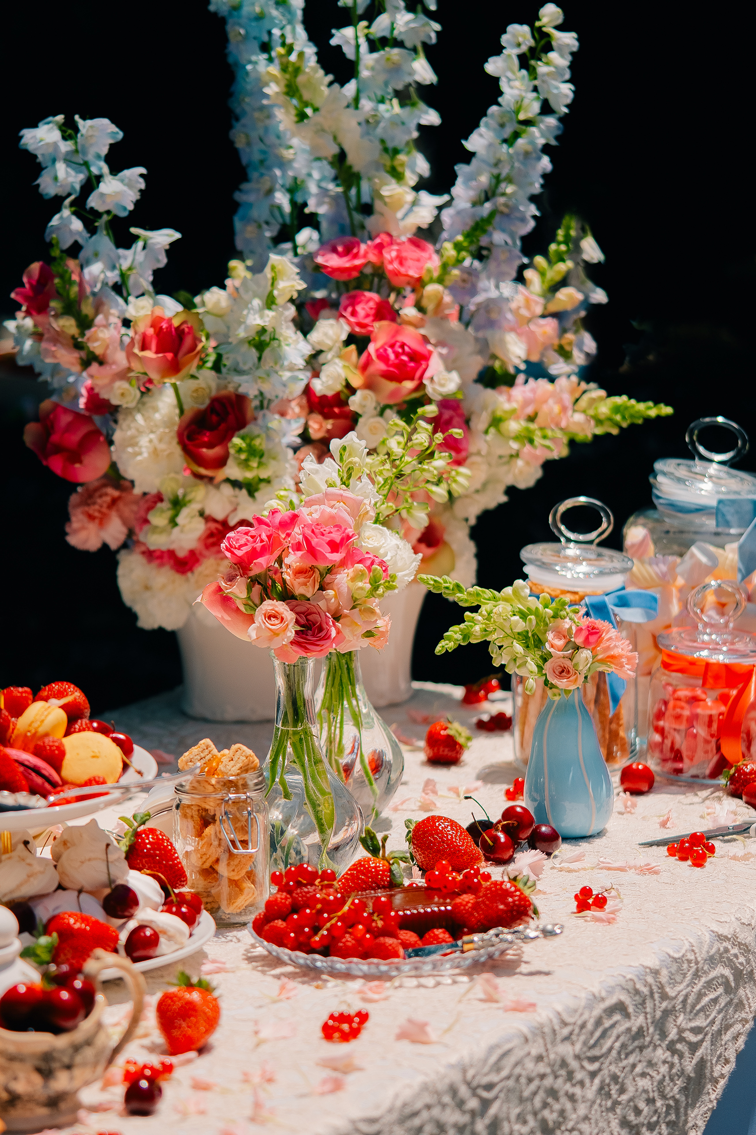 Elegant Floral Table Setting with Berries And Sweets Beautifully arranged table with vibrant flowers, fruits, and desserts, perfect for special occasions.