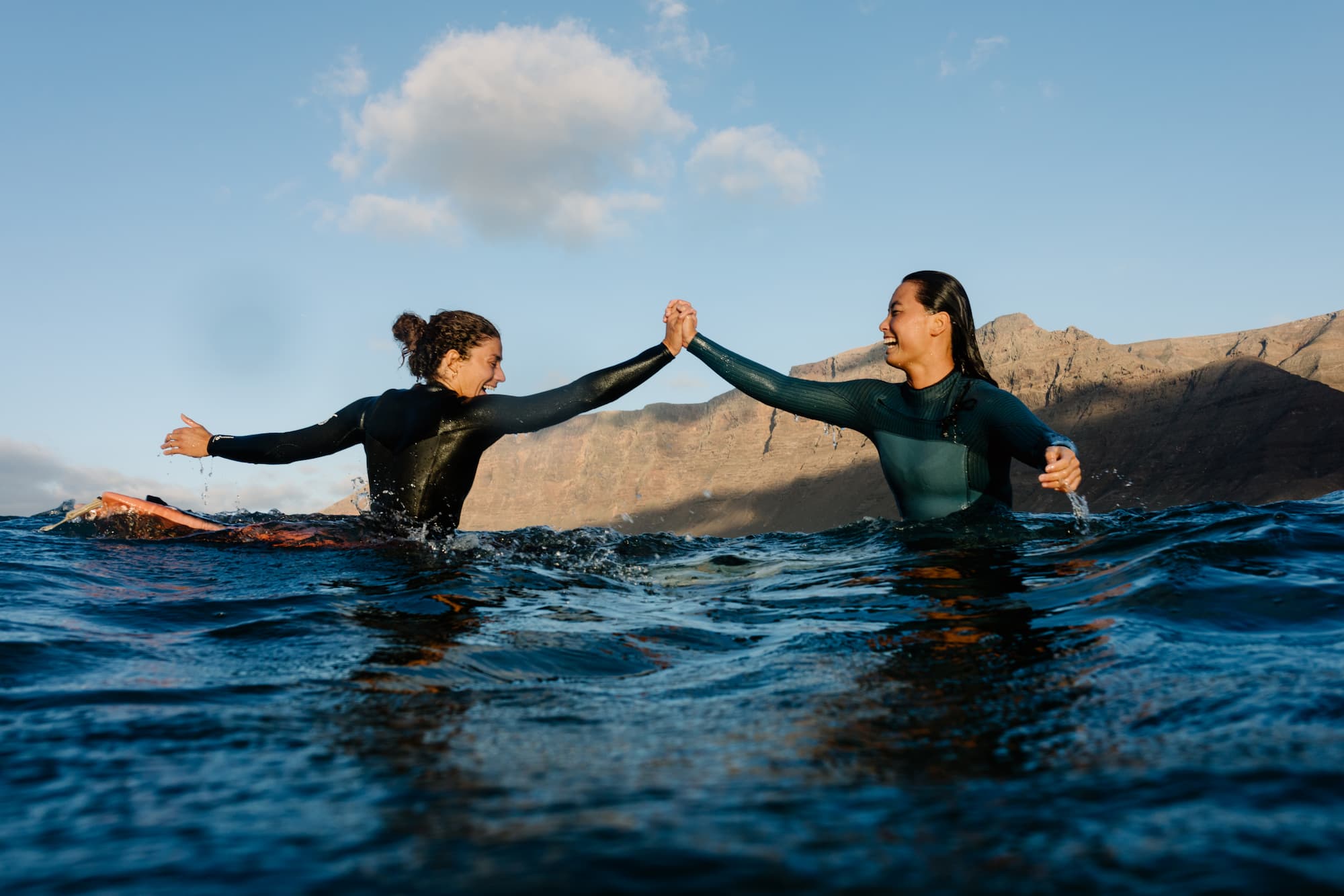 Female surfers happily high-fiving during a surfing practice session