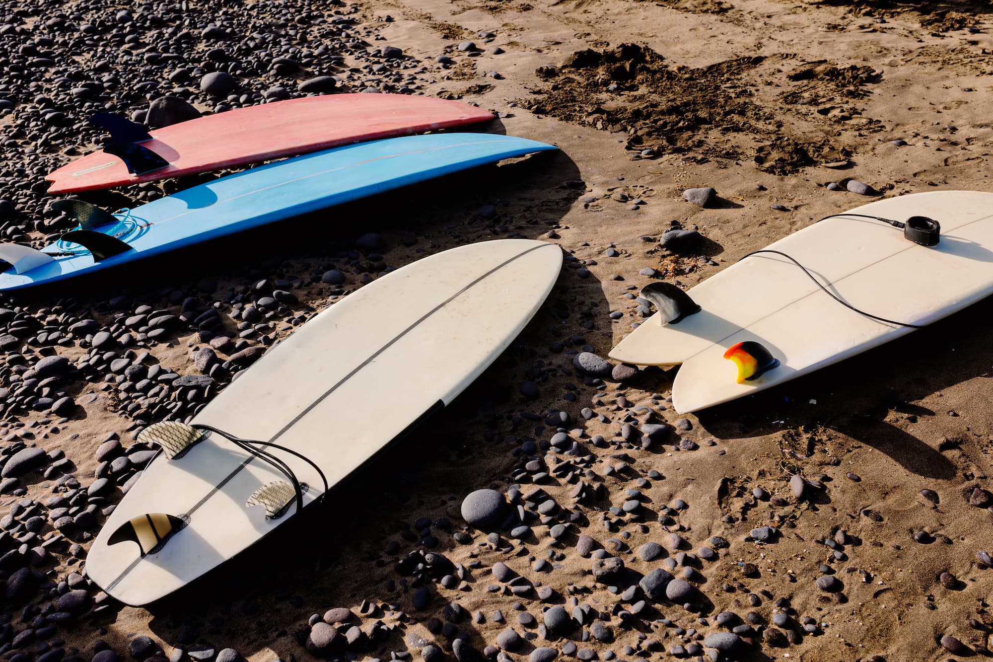 Surfboards laid out on the sand of a rocky beach