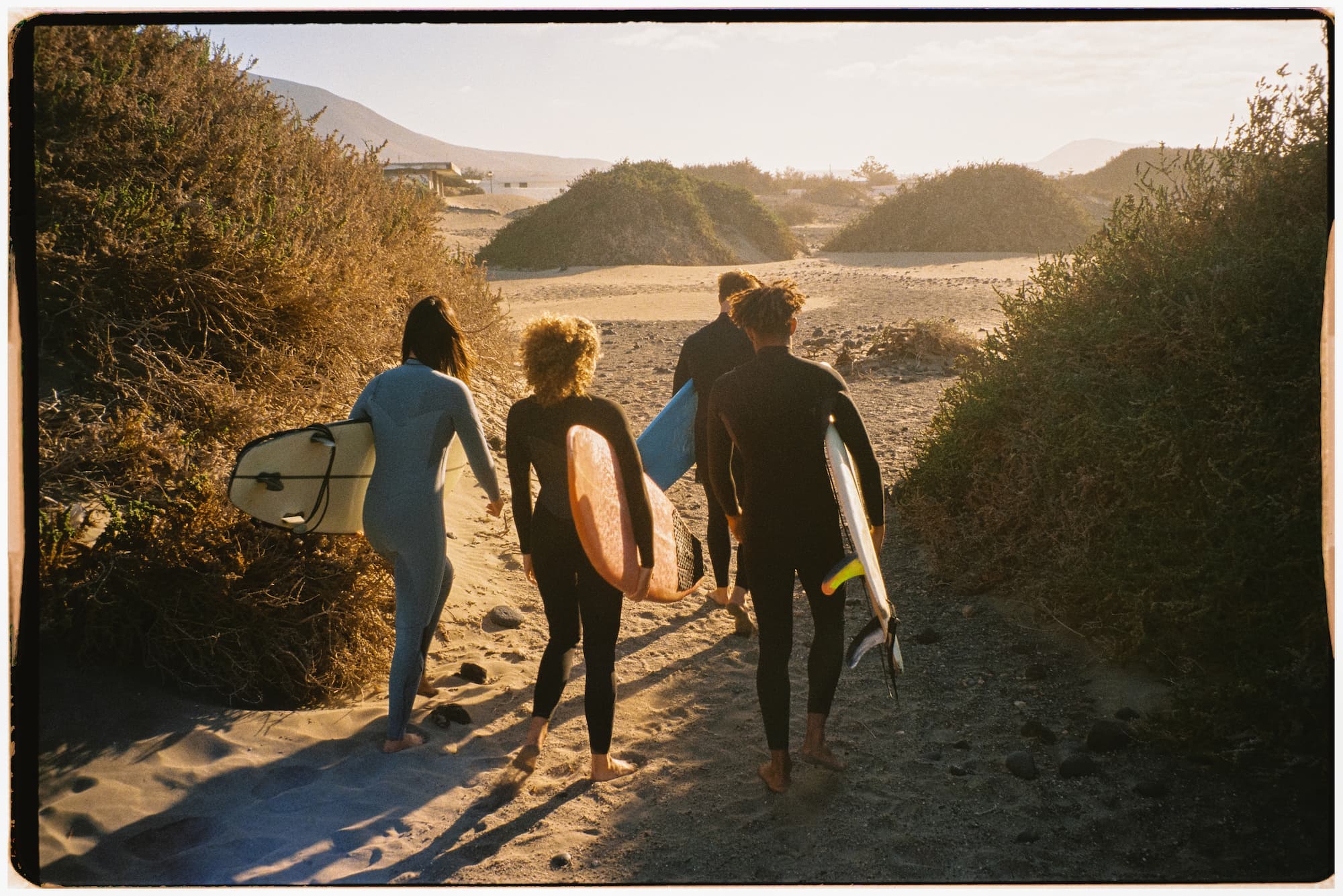 Full body film shot of a diverse group of surfers walking to the ocean