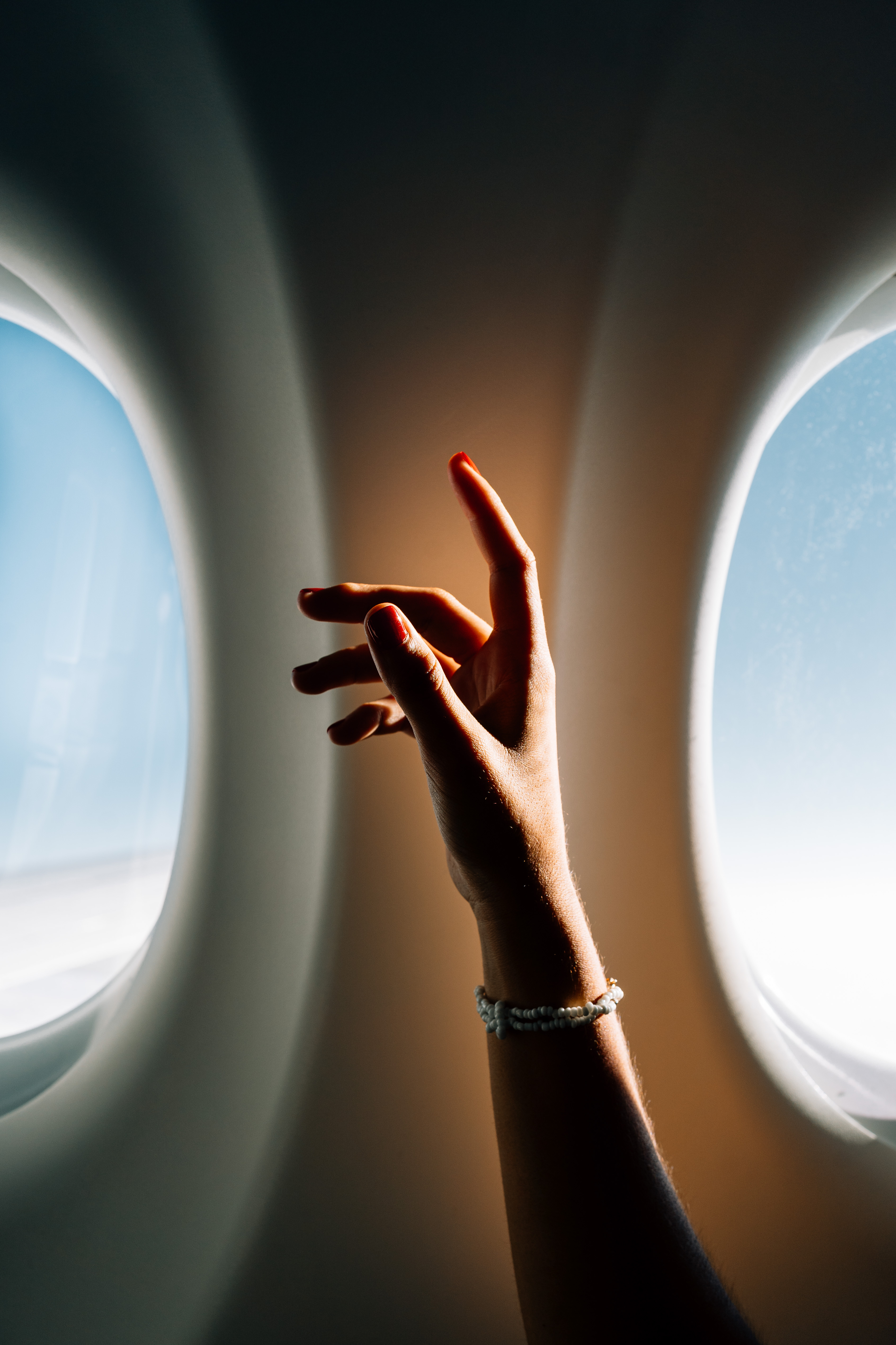 Crop female raising arm with elegant bracelet near windows of plane during trip.