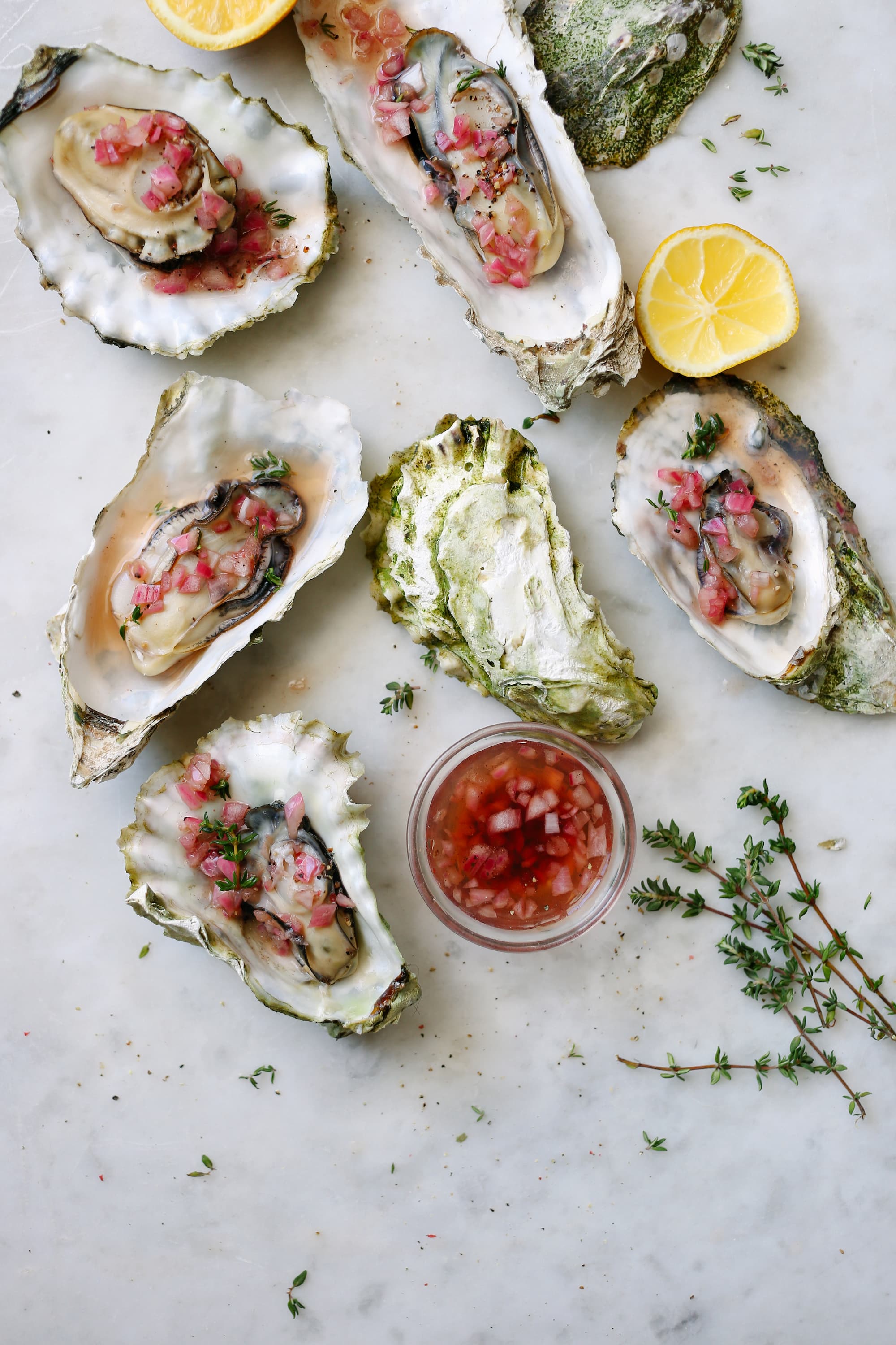 Cooked oysters with mignonette sauce and lemon Composition with cooked oysters with mignonette sauce and lemon with thyme on white marble