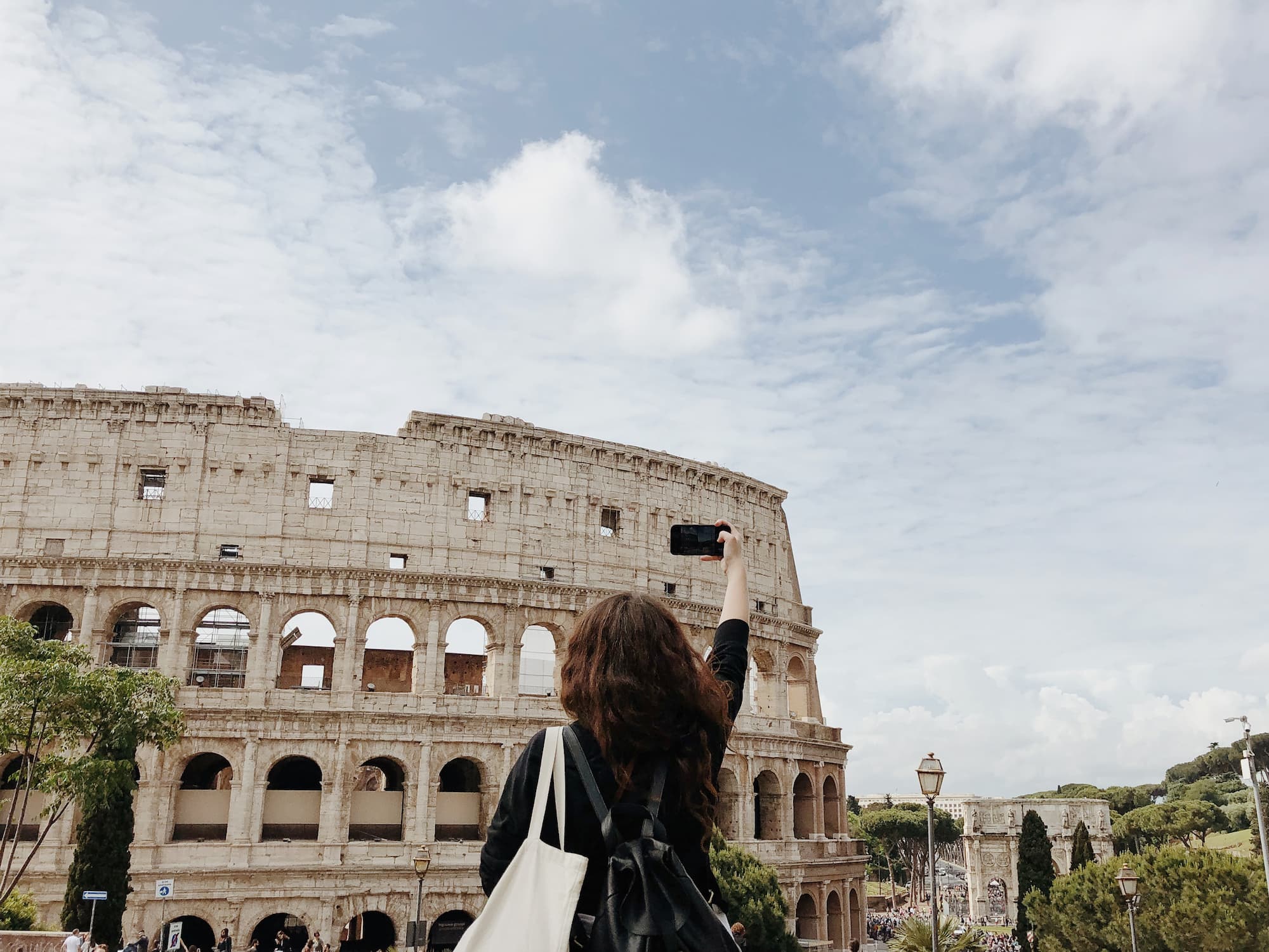 Taking pictures on smartphone. A real person in front of Colosseum in Rome taking travel pictures.