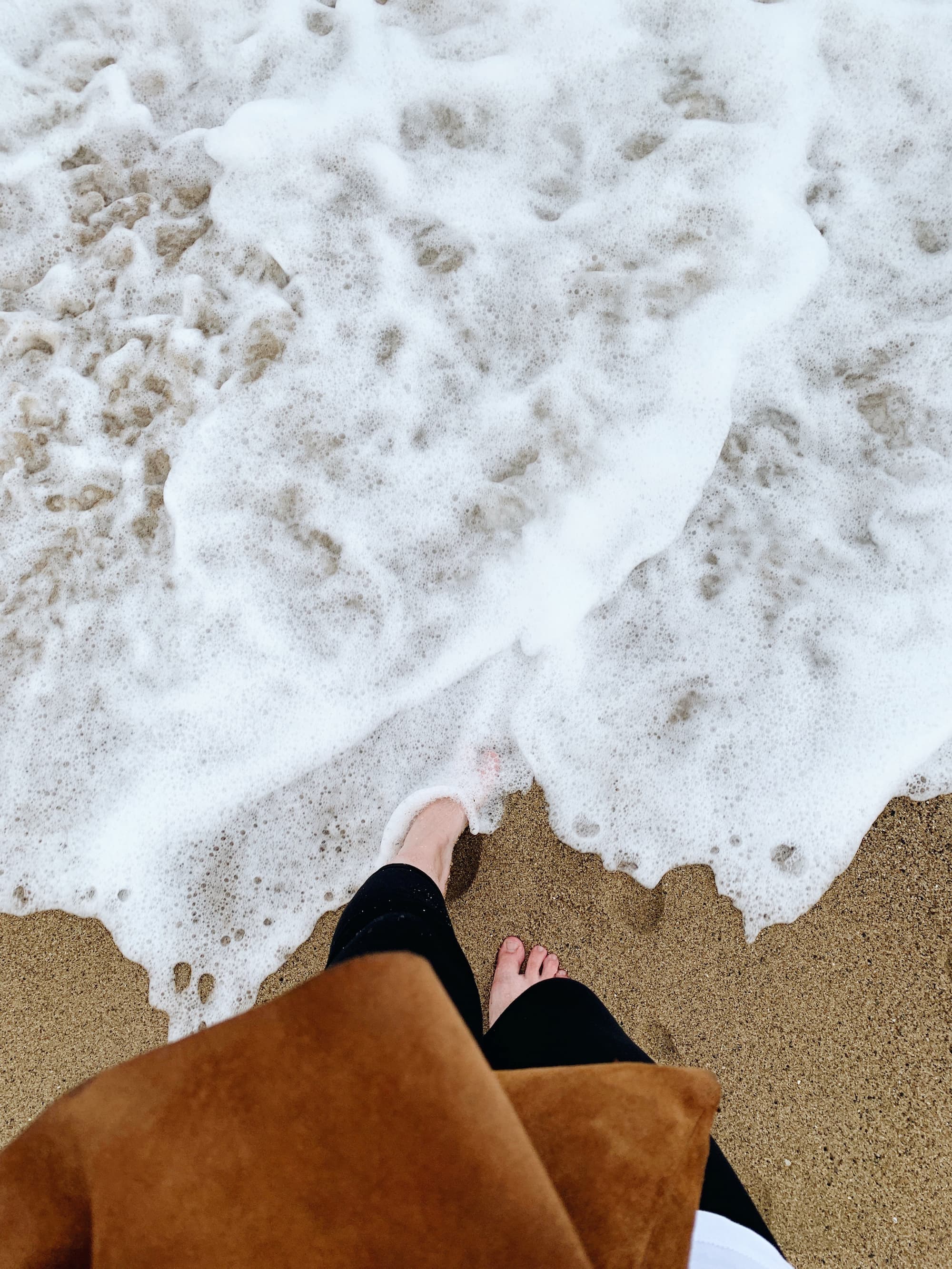 Fun at the seashore A barefoot woman is playing with the sea foam at the seashore
