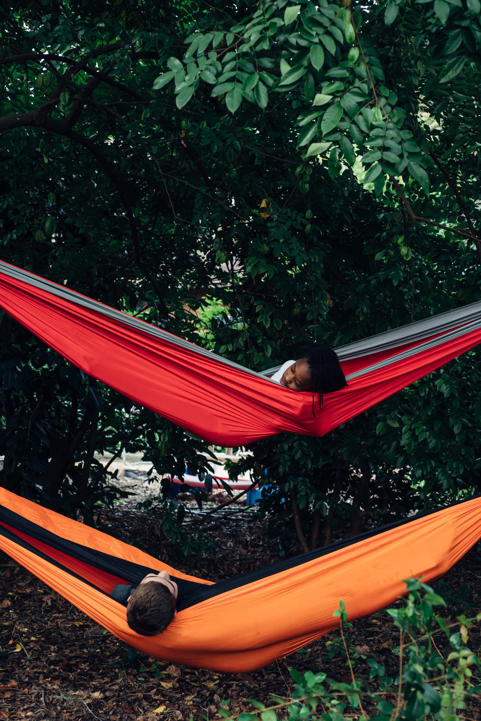 Black girl and Caucasian boy hanging out in hammocks
