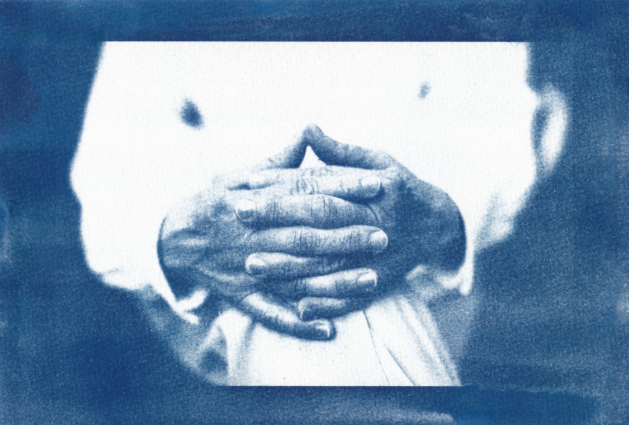 A cyanotype print of hands in a relaxed and gentle pose, utilizing soft textures and calming blue hues.