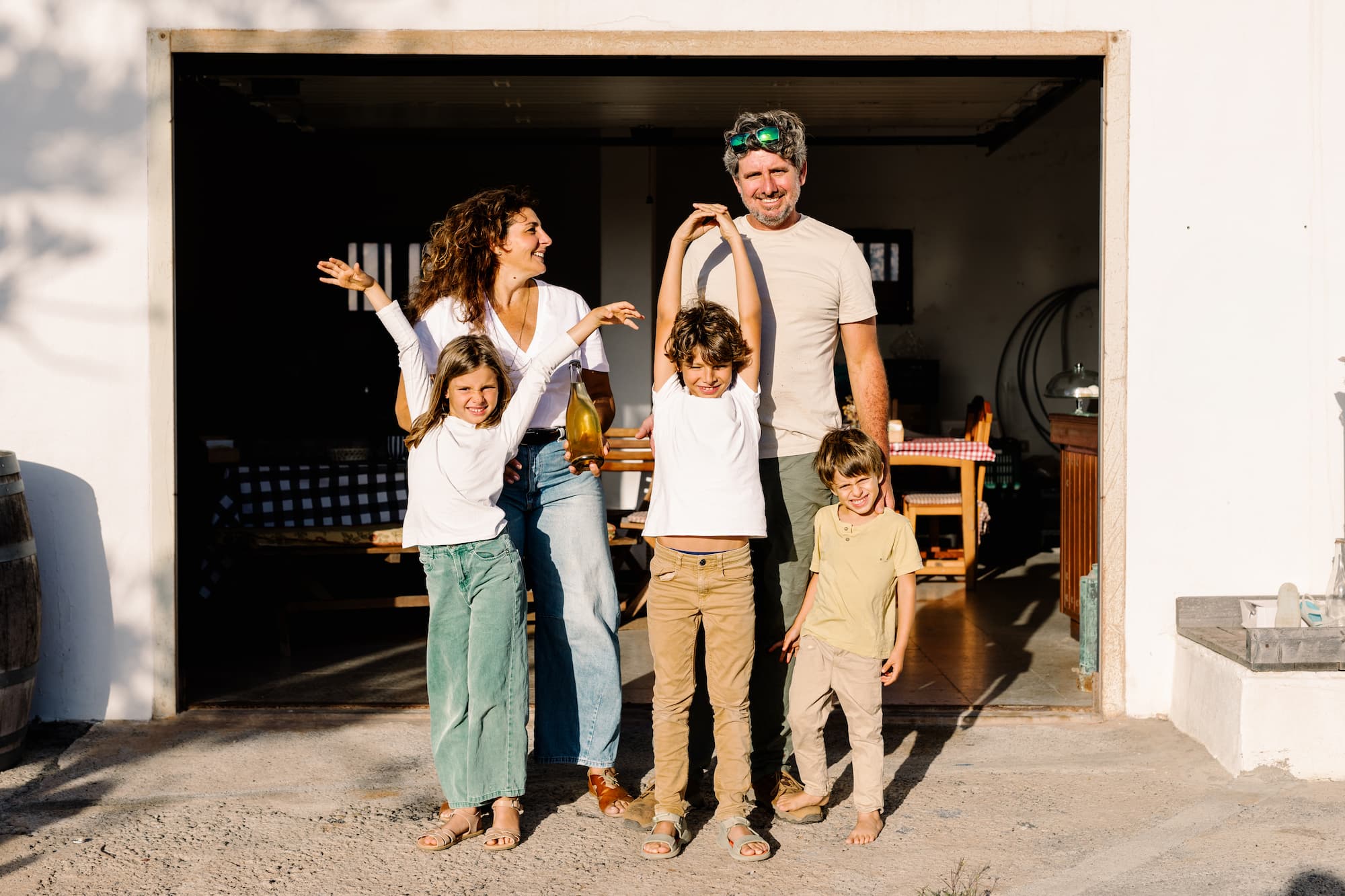 A portrait of a local family standing in front of their quaint organic wine cellar on a sunny afternoon in Lanzarote, Canary Islands.