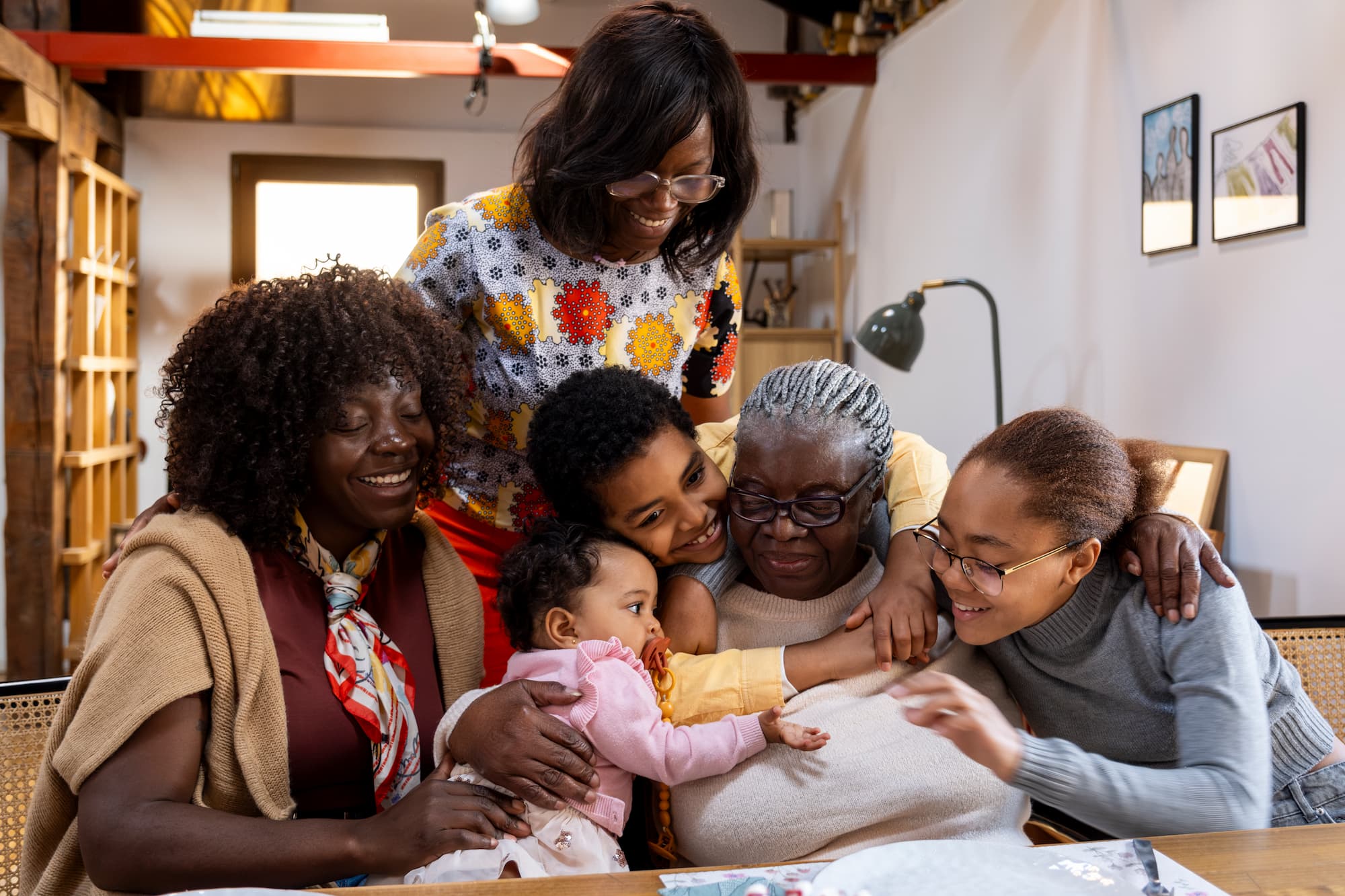Grandchildren hugging grandmother during family celebration at bright home living room.